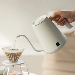 Vit elektrisk vattenkokare med smal pip och trähandtag för precision i bryggningen från Timemore, allt om kaffe.