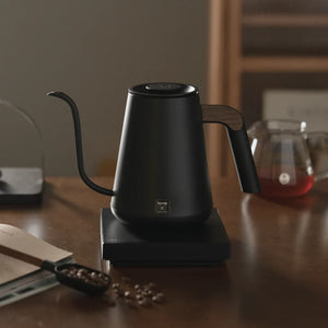 Svart elektrisk vattenkokare med smal pip och trähandtag för barista och brygg tillbehör från Timemore, allt om kaffe.