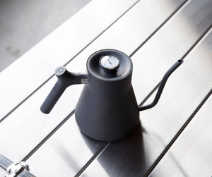 Matt svart vattenkokare med smal svanhals och inbyggd termometer, bryggtillbehör, allt om kaffe.