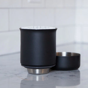 Matt svart handbryggare med platt botten och rostfritt stål, del av Fellow och EspressoGear, allt om kaffe.